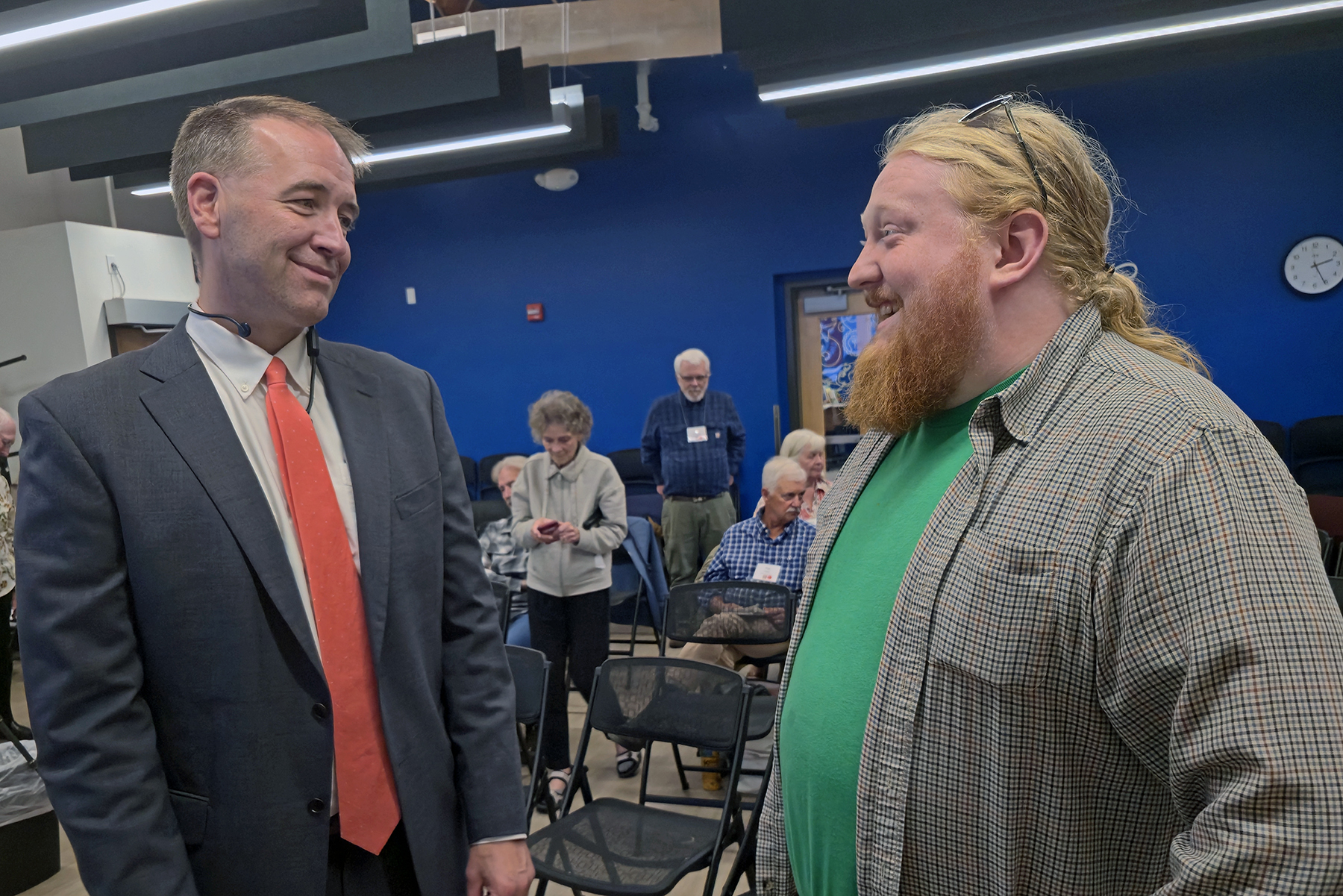 Commissioner Gabe standing with Benton County's SOS during a public meeting, with chairs and citizens in the background