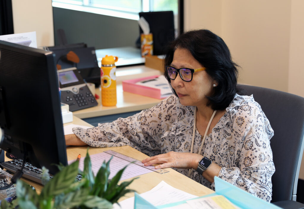 A woman works at a desktop computer in an office setting